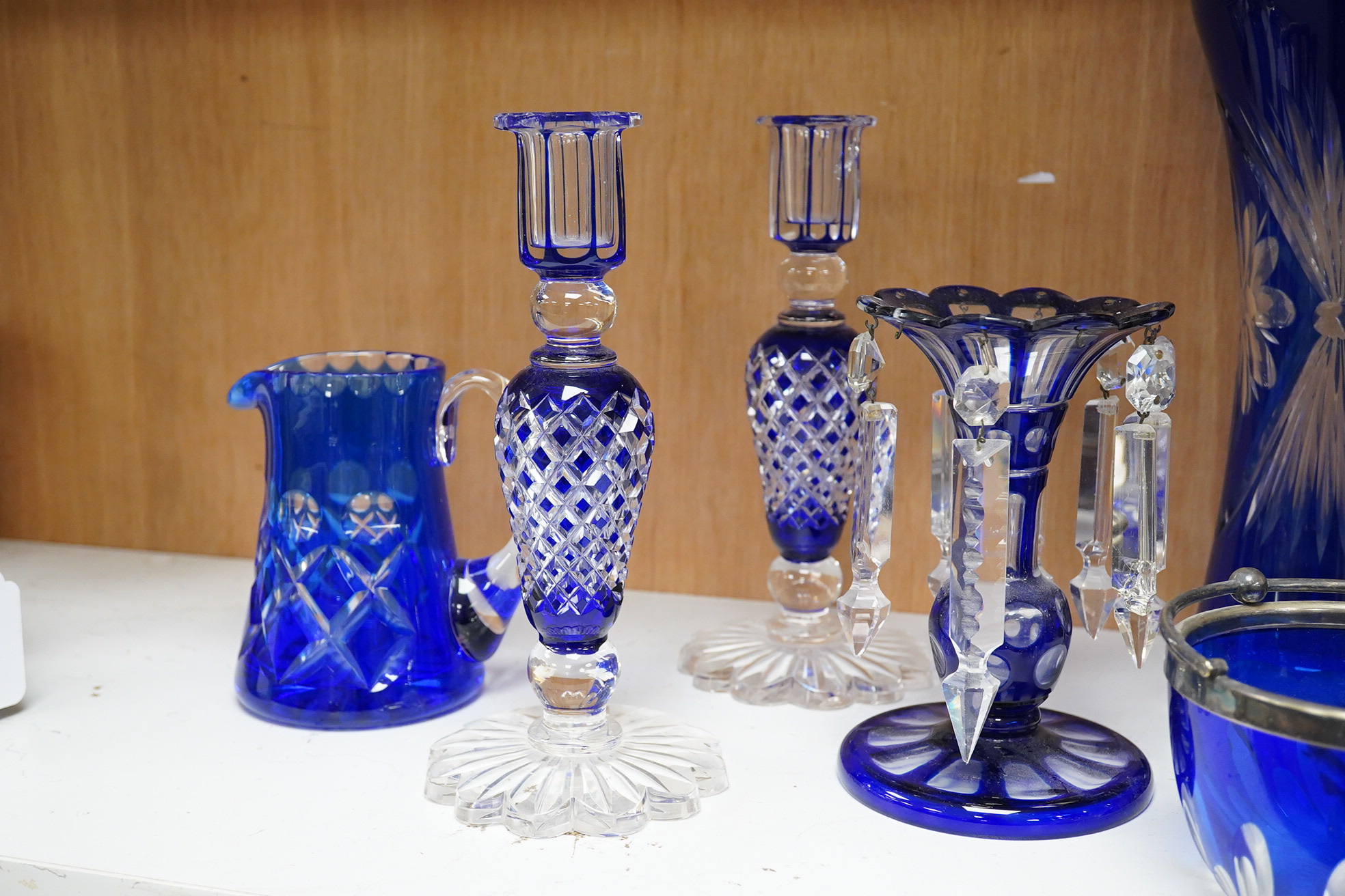 A pair of blue overlaid glass table lustres with drops and other blue overlaid glassware to include a pair of candlesticks and vases, largest 27cm high